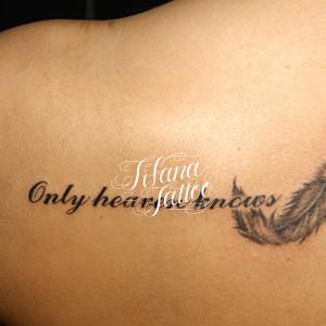 羽と文字のタトゥー