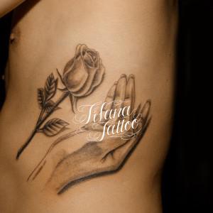 バラに手を添えたタトゥー
